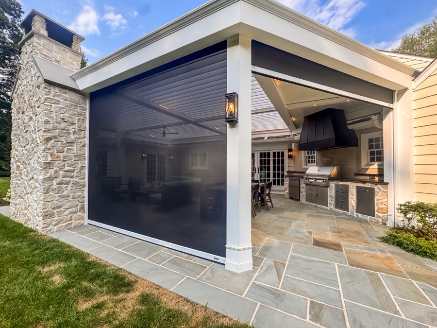 Motorized screen shades enclosing an open-air pergola in the evening