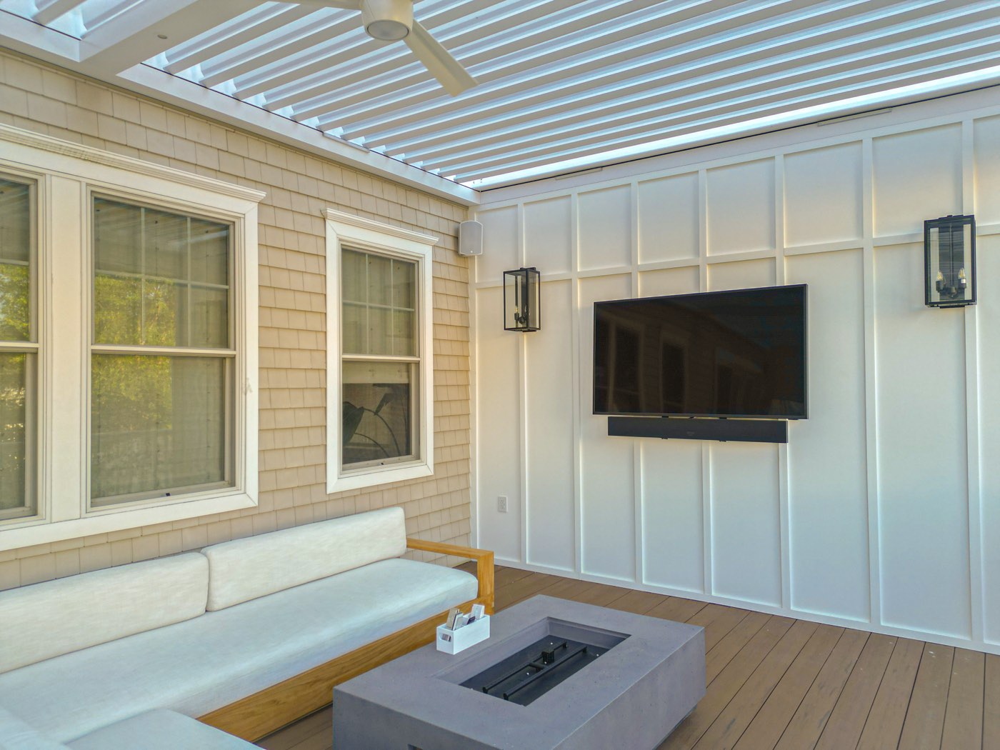 TV mounted on a privacy wall beside a fire feature under a Breslow louvered pergola, Monmouth Beach, NJ