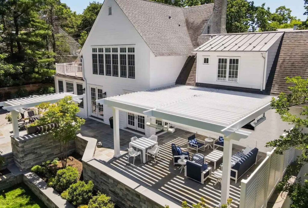 A timeless classic pergola with white louvers and elegant outdoor seating, complementing a traditional home design and creating a bright, inviting patio space.