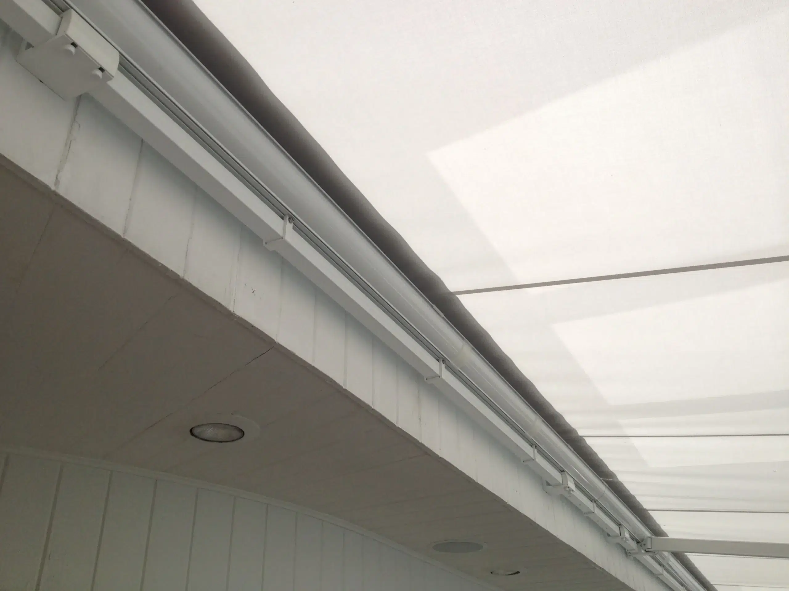 Detailed close-up view of a retractable awning cassette and track mechanism installed along a home’s exterior ceiling.