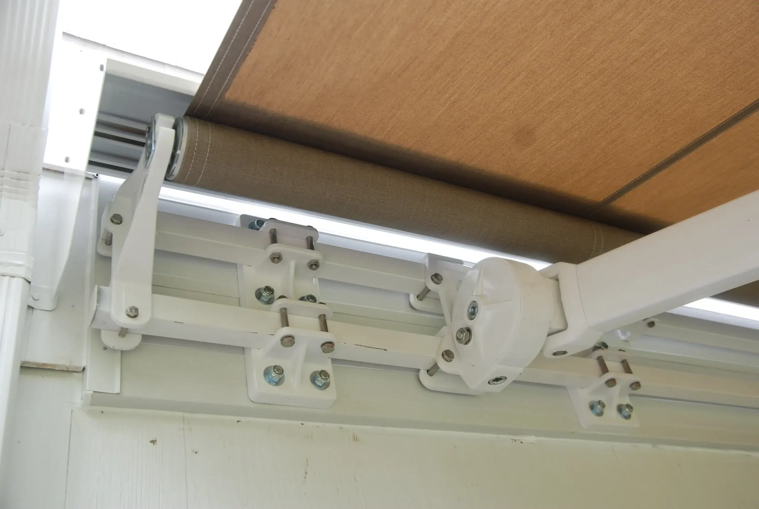A close-up of retractable awning hardware showing the mounting bracket and support arms attached to the structure.