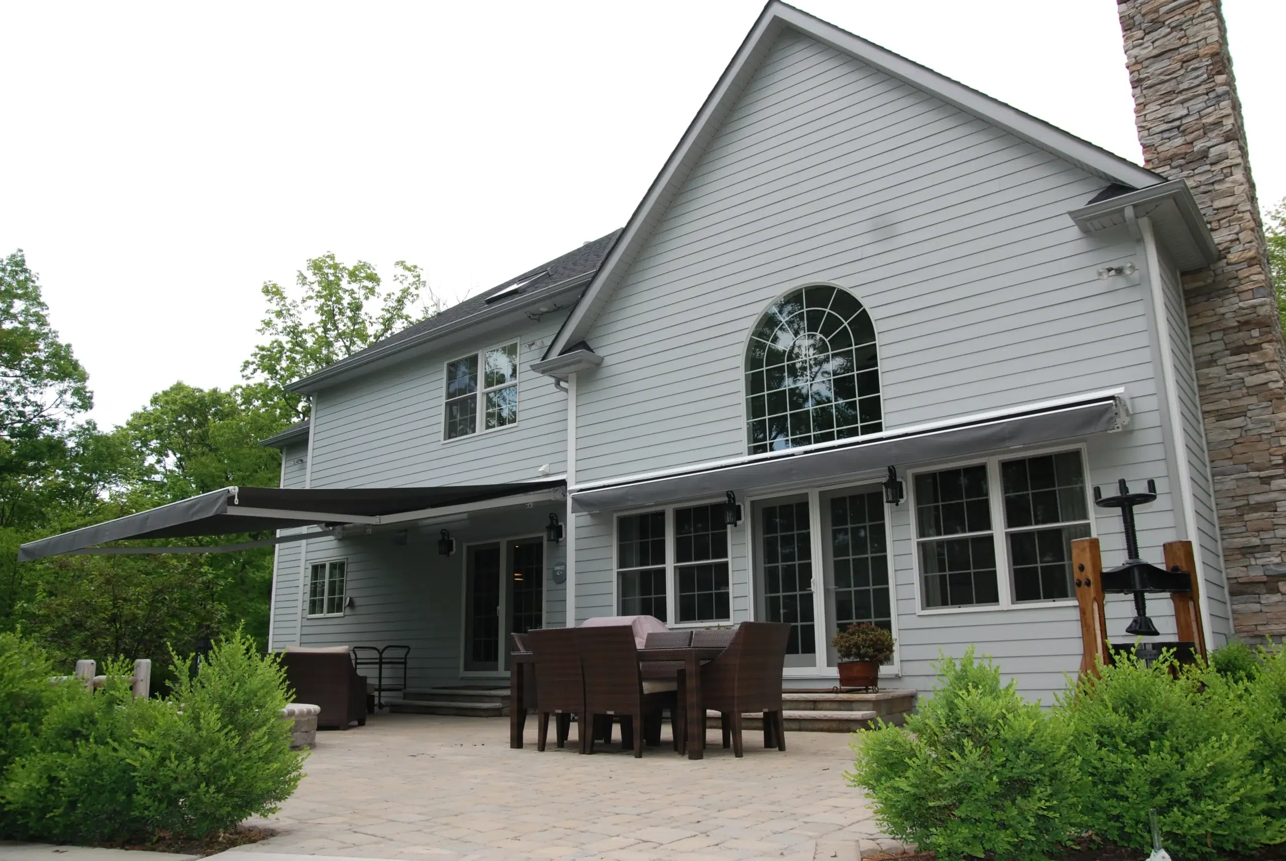 A wide retractable awning installed on a residential patio with an outdoor dining setup, blending modern style with comfort.