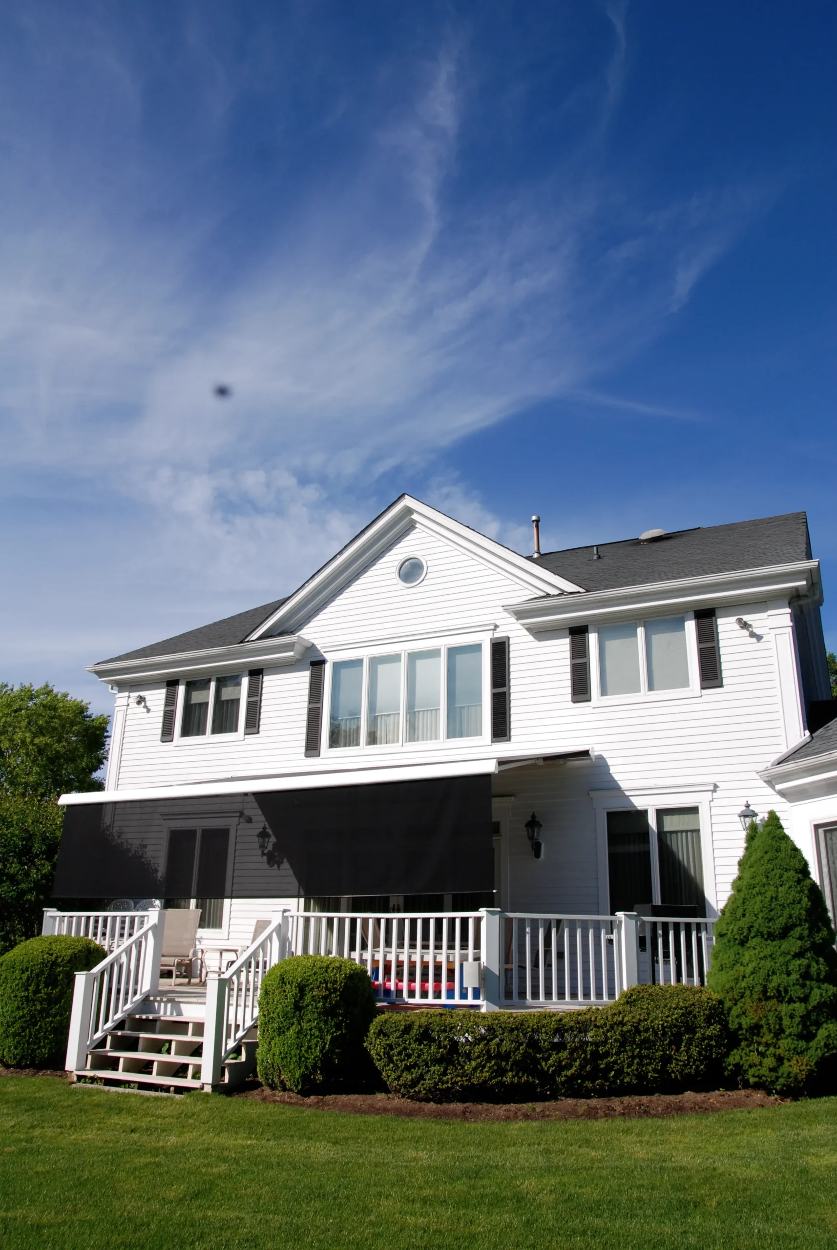 A retractable awning installed on the back of a home, creating a shaded outdoor space for seating.