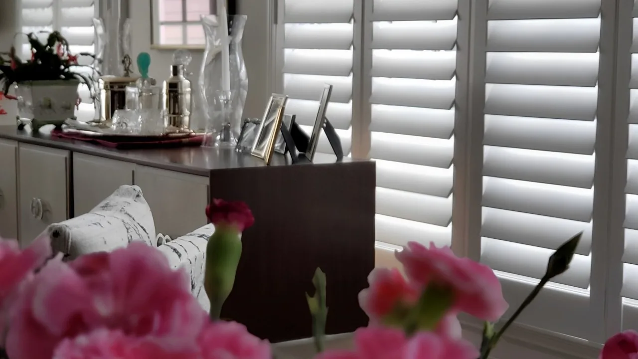 Close-up view of a bedroom dresser and décor with white plantation shutters filtering natural light in the background.