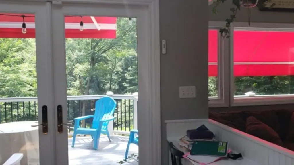 Indoor view looking out through glass doors toward a patio with bright red retractable awnings and outdoor seating.