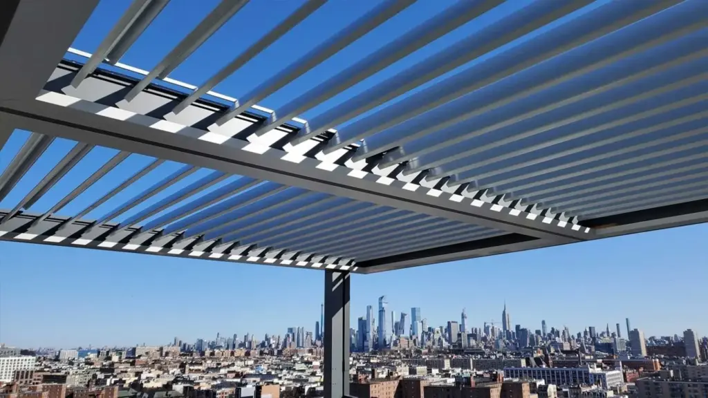 Adjustable-louver motorized pergola installed on a rooftop terrace overlooking a panoramic city skyline.