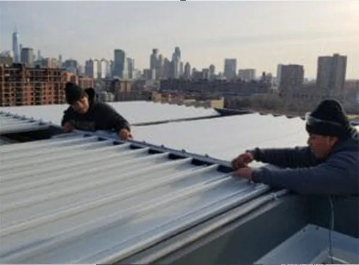 Technicians installing aluminum louvered roof panels on a rooftop terrace with a city skyline in the background.